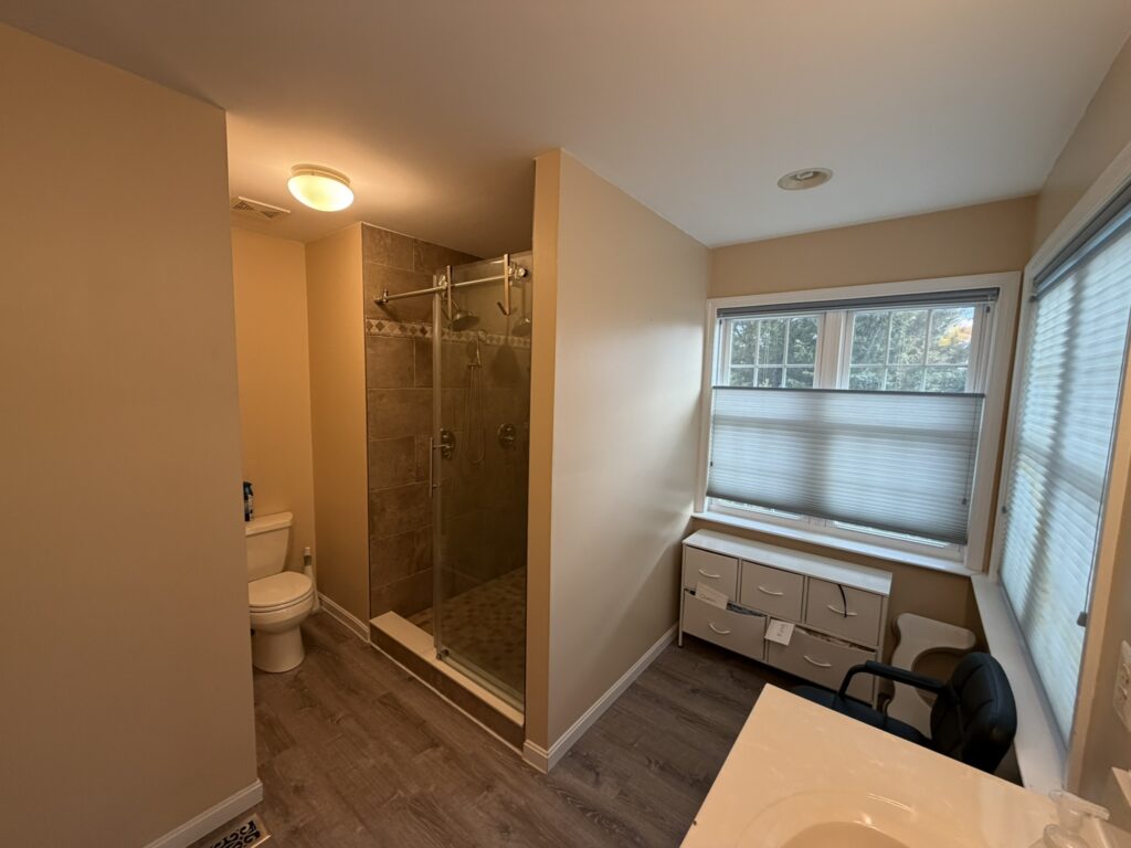 Updated bathroom with glass door, walk-in shower, toilet alcove, and large window with natural light.