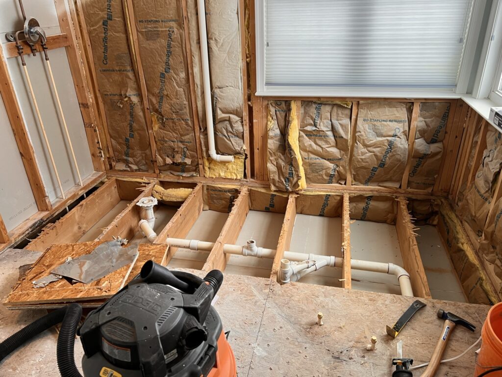 New bathroom floor framing and updated drain plumbing installed during remodel